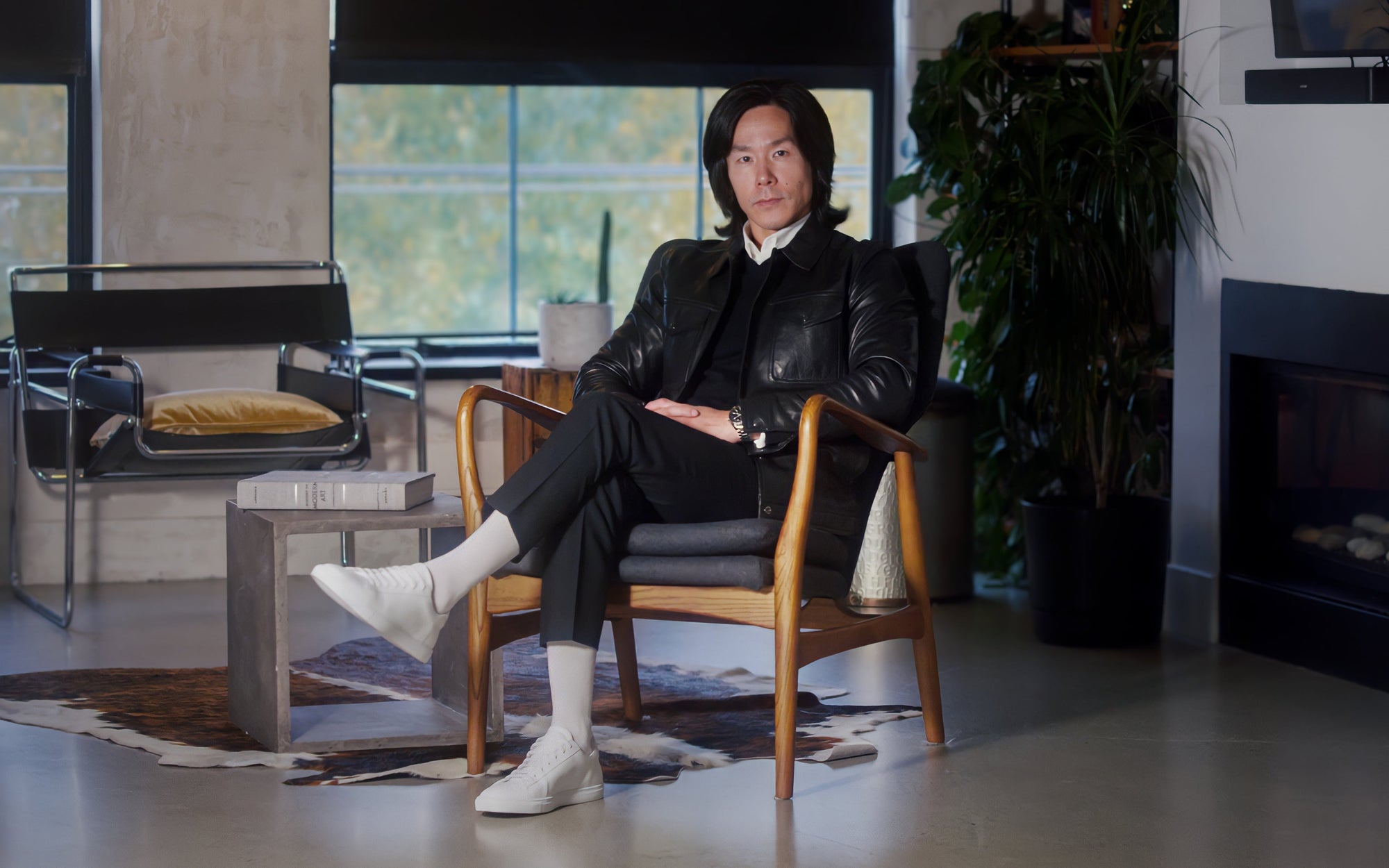 Man wearing white Italian leather sneakers seated in a modern interior, minimalist style footwear by OLEN
