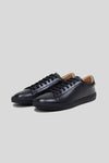 Three-quarter studio view of a pair of Olen Città low-top sneakers in black calfskin leather with neutral tan lining.