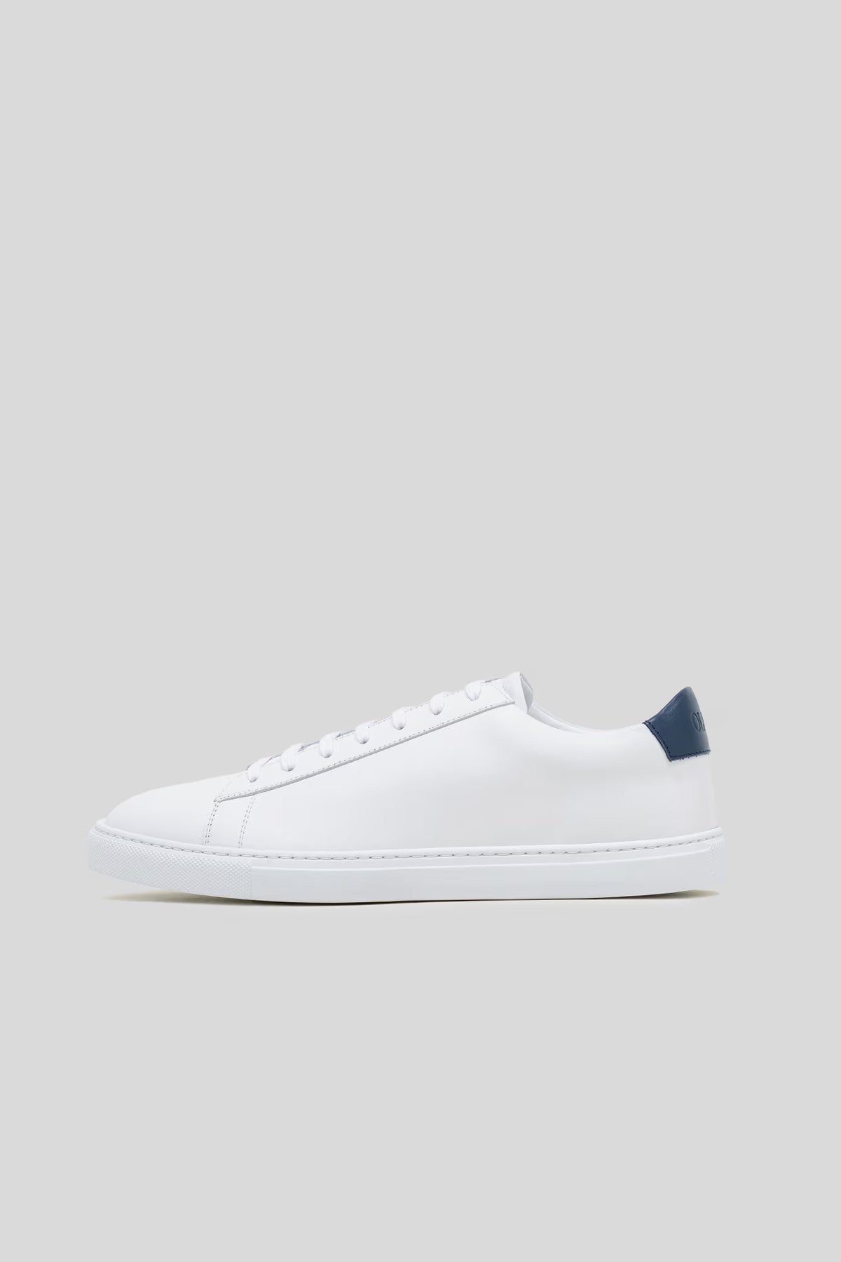 Side profile studio view of the Olen Città low-top sneaker in white calfskin leather with a navy heel tab.