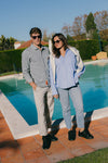 Full-length poolside lifestyle shot of a couple wearing black calfskin Olen Città sneakers with casual resort outfits.