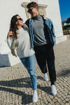 Couple smiling and walking arm-in-arm on a cobblestone street wearing matching Olen Città low-top sneakers in white calfskin leather.