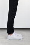 Side profile view of the Olen Città low-top sneaker in white calfskin leather worn on-foot by a male model with black trousers.