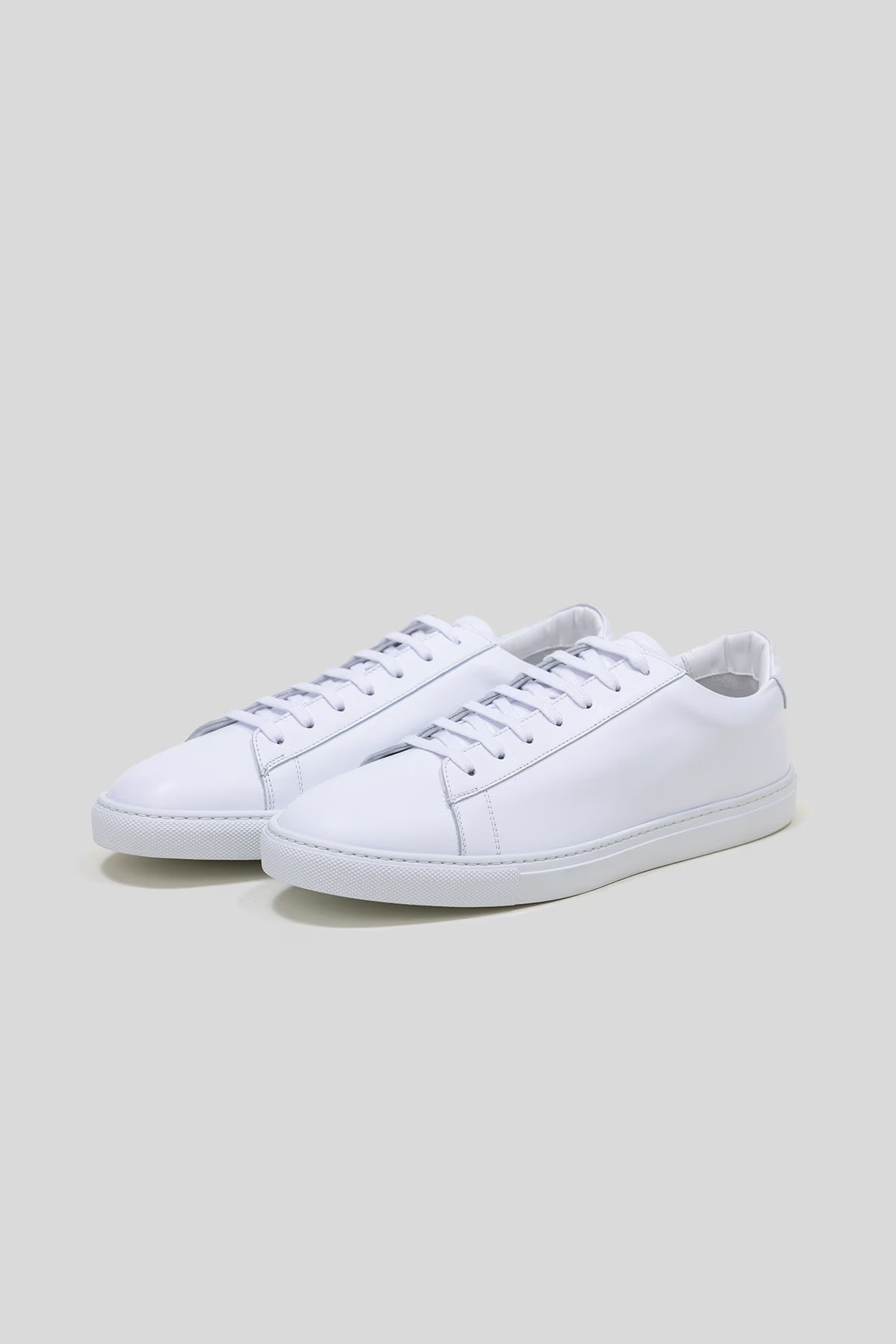 Three-quarter studio view of a pair of Olen Città low-top sneakers in white calfskin leather.