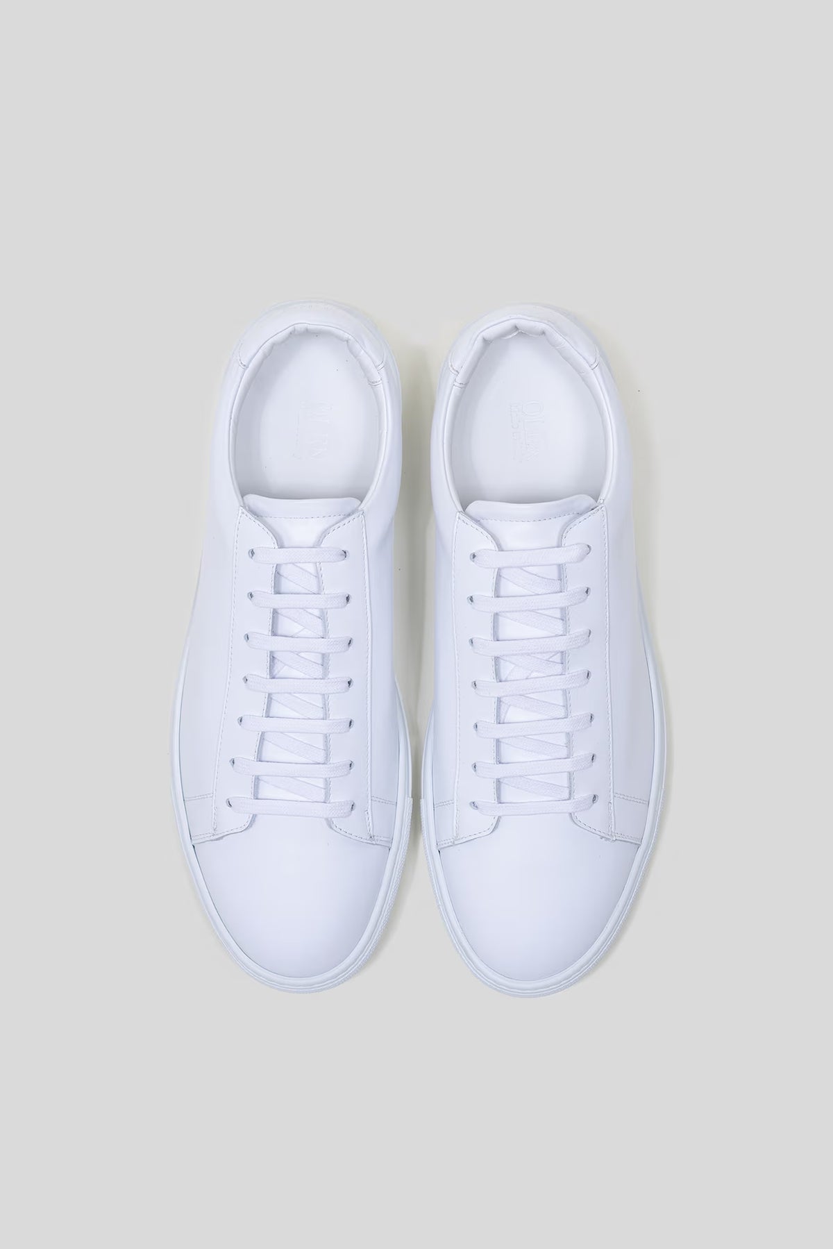 Top-down studio view of a pair of Olen Città low-top sneakers in white calfskin leather.