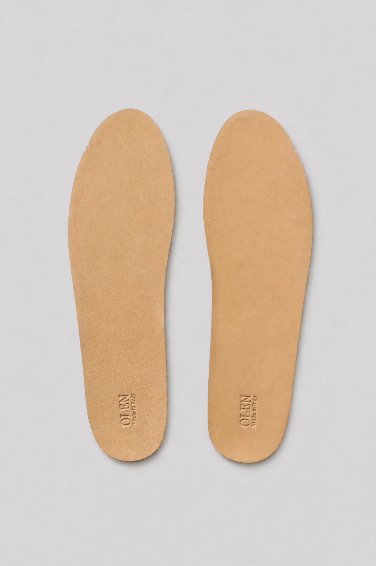 Top view of a pair of tan lambskin insoles with embossed OLEN Made in Italy logo on a light grey background